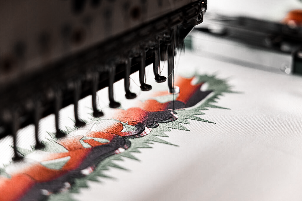 Digital embroidery machine stitching a multicolor design on fabric using Coloreel thread-coloring technology